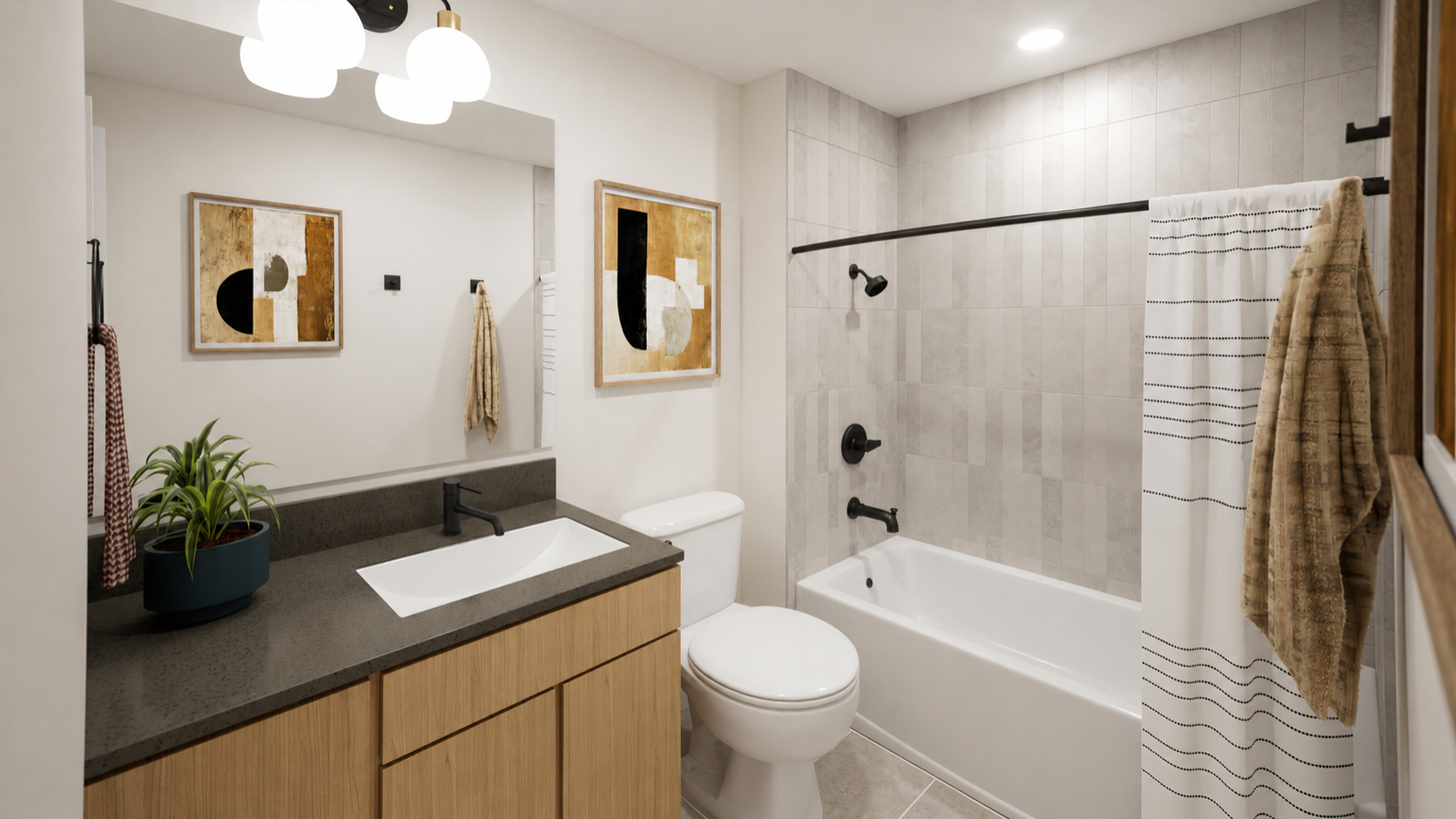 Modern bathroom in Rambler College Park North with wood cabinets, black fixtures, a white sink, toilet, bathtub with a striped shower curtain, two abstract art pieces, a potted plant on the counter, and towel hanging on the wall.