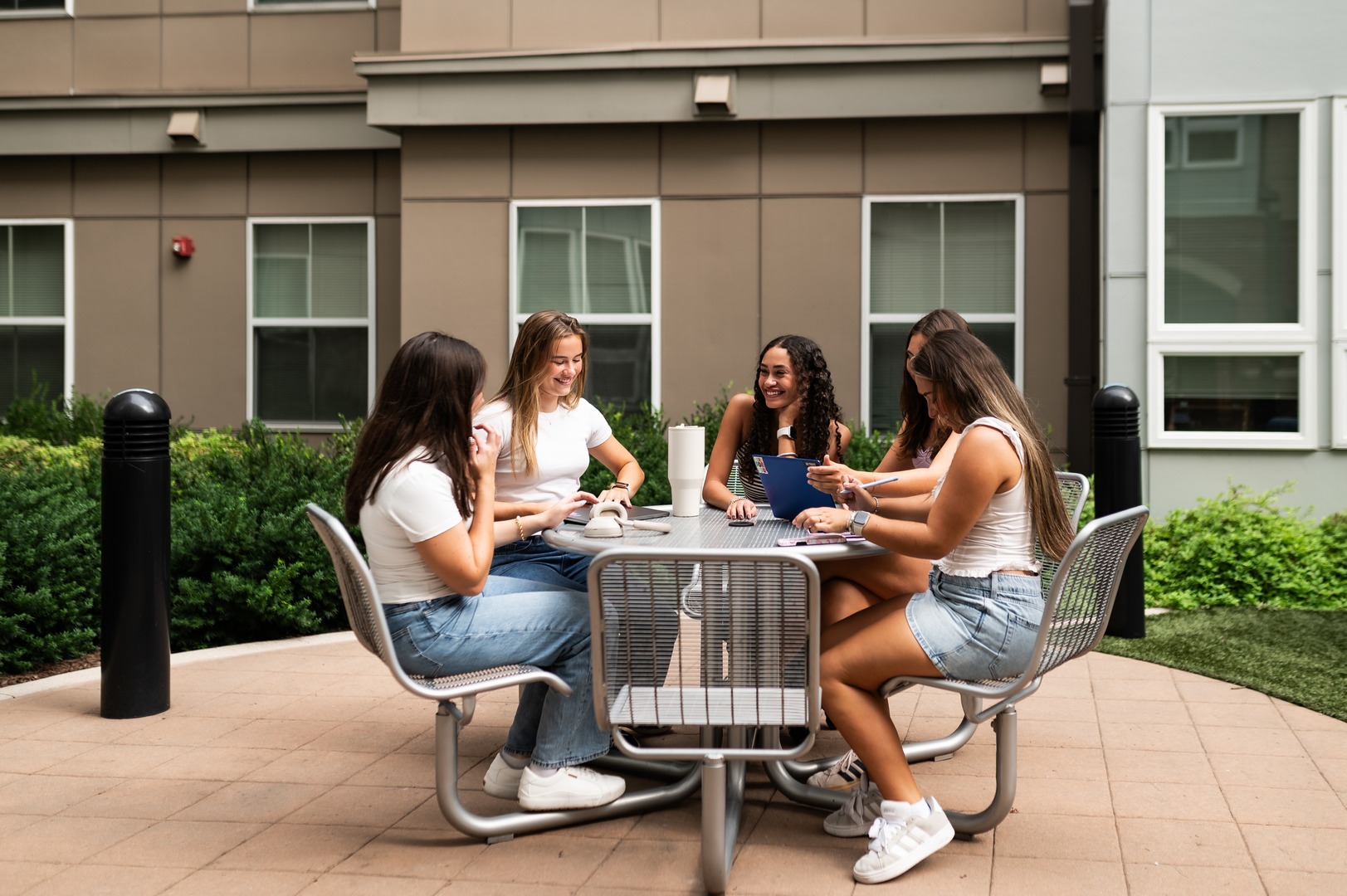 four girls sitting and smiling while studying outside at Rambler College Park South