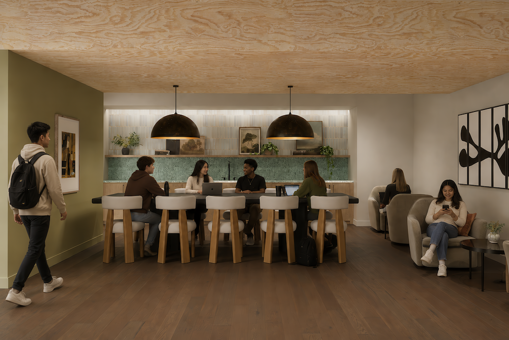 Several people sit and talk at a high counter in a modern lounge at Rambler College Park South, surrounded by wooden floors, soft lighting, and greenery; others relax on armchairs or walk by.