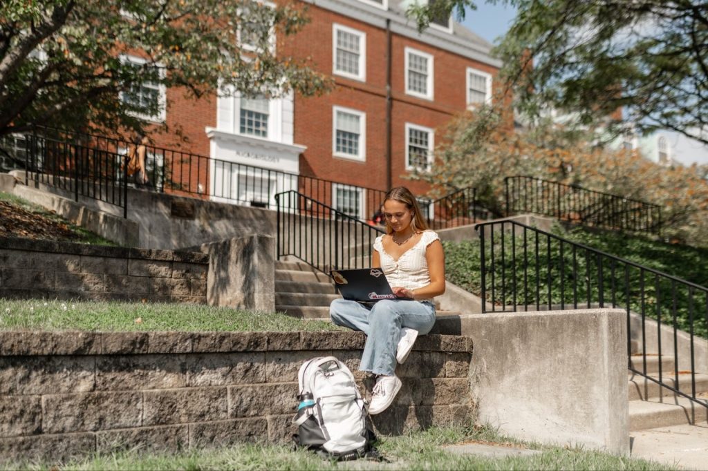 Student works on a laptop outside on campus.
