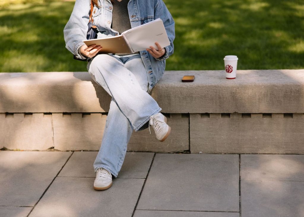 A student sits and reads through a notebook. 