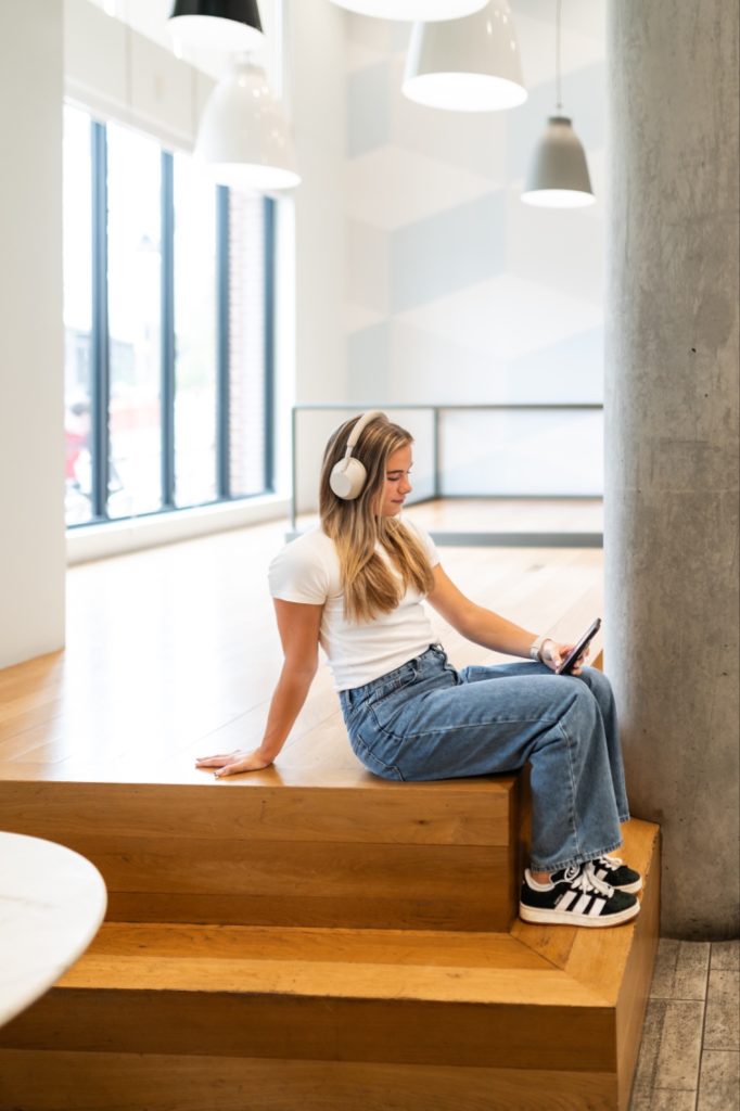 Student listening to music in an off-campus apartment lobby.