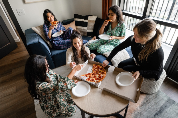 New residents enjoy pizza together in their living room at Rambler College Park.