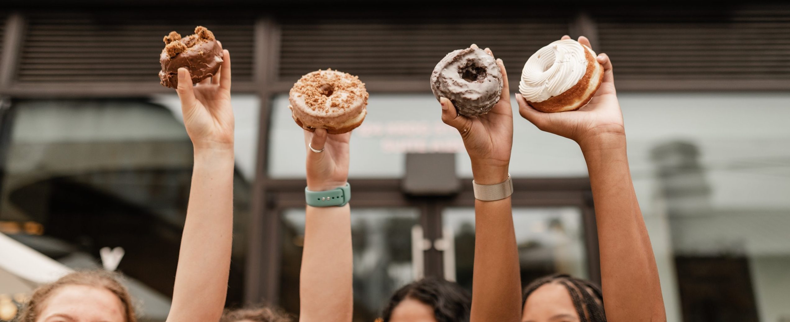Hands holding up donuts from a College Park bakery